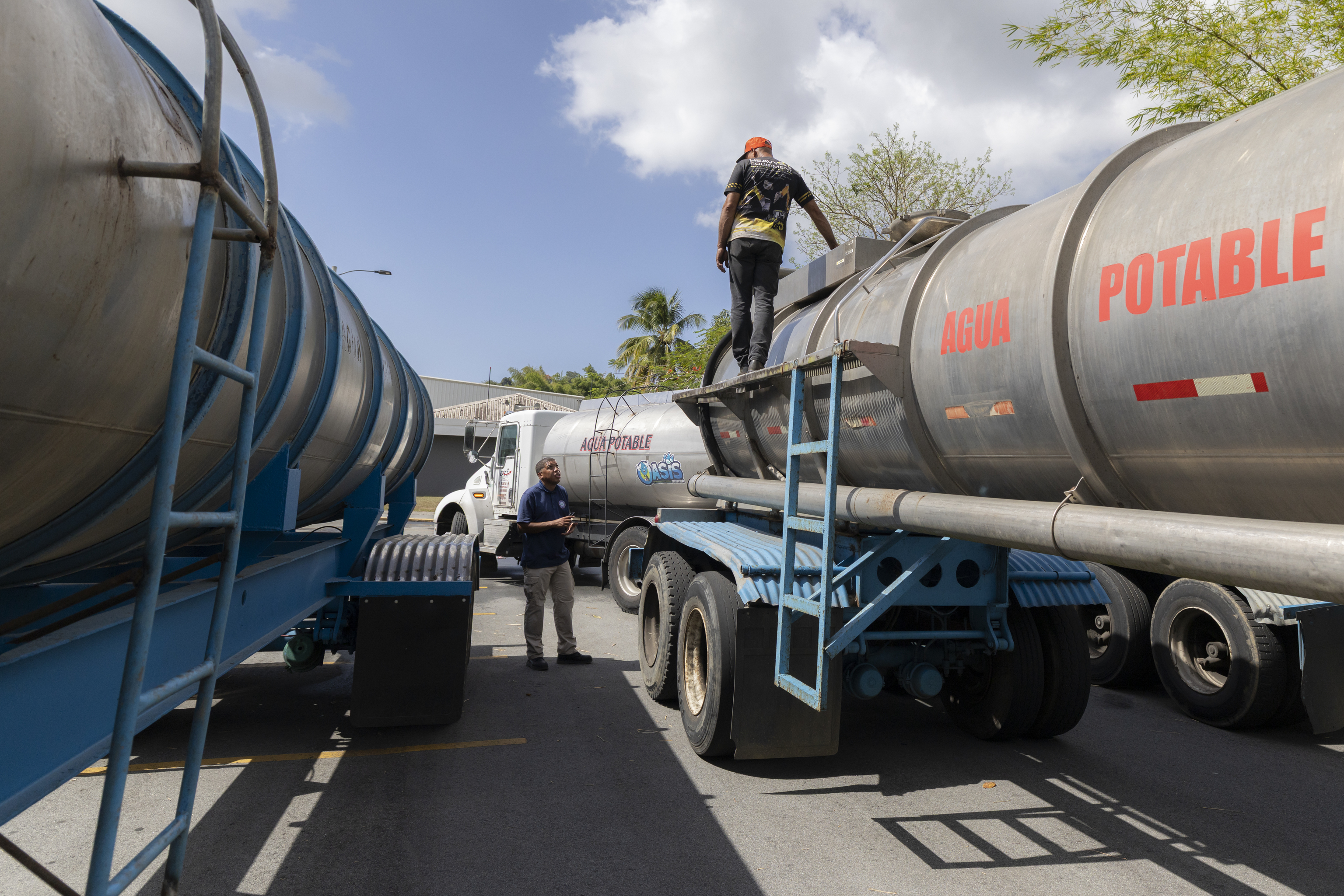Peor sequía en una década obliga a cortes de agua en Puerto Rico cada dos días 3 Un trabajador camina sobre un camión cisterna con la inscripción "Agua Potable" mientras se conectan las mangueras entre los vehículos.